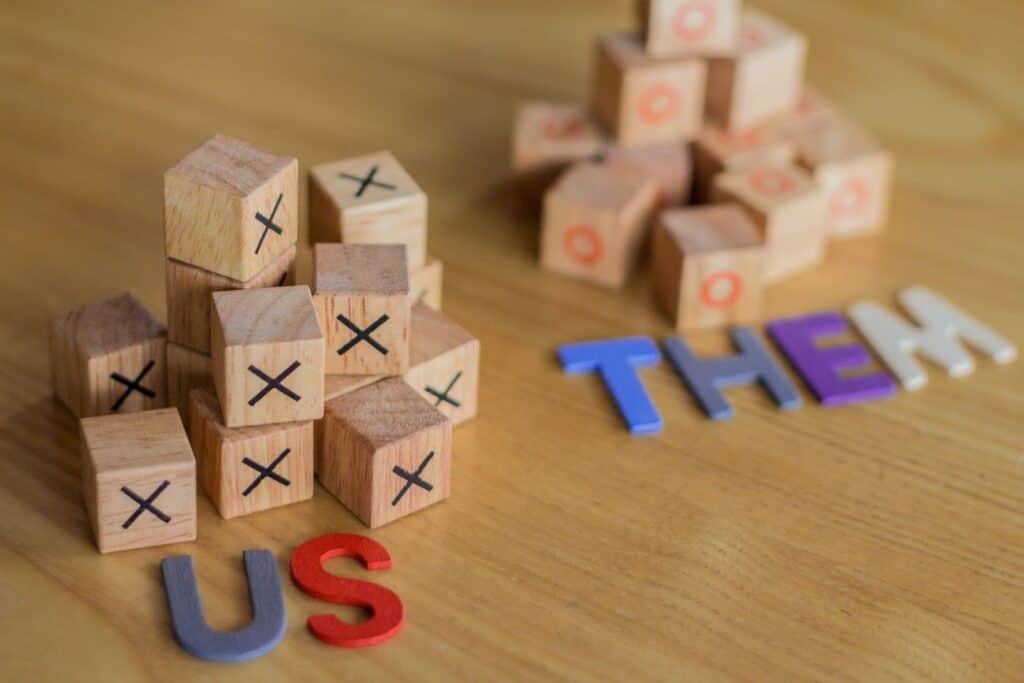 Illustration of toy blocks in two piles labeled "us" and "them"