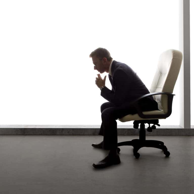 Man in suit sitting alone thinking in office chair